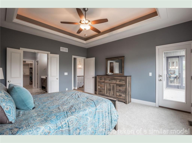 Carpeted bedroom with ceiling fan and a tray ceiling