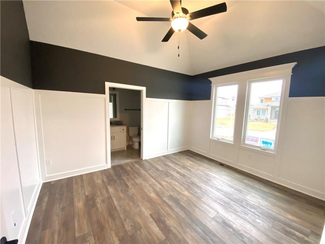 Unfurnished bedroom with vaulted ceiling, ceiling fan, hardwood / wood-style flooring, and ensuite bath