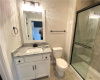 Bathroom featuring tile flooring, a shower with door, vanity, and toilet