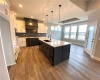 Kitchen featuring decorative light fixtures, dark hardwood / wood-style floors, custom exhaust hood, a kitchen island with sink, and sink