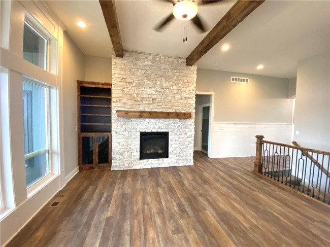 Unfurnished living room featuring ceiling fan, a fireplace, beam ceiling, and dark hardwood / wood-style flooring